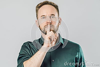 Serious caucasian man holding index finger over mouth saying shh Stock Photo