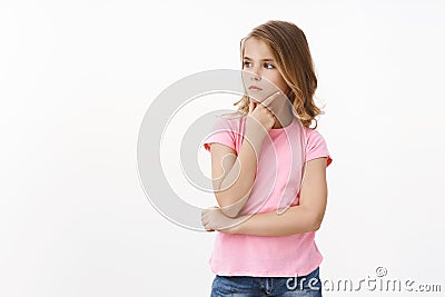 Serious clever lovely little girl with blond hair, daughter thinking what draw, search inspiration, touch chin Stock Photo