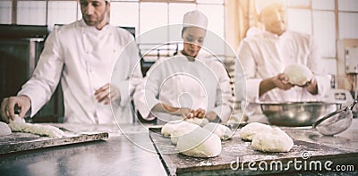 Serious colleagues kneading uncooked dough Stock Photo