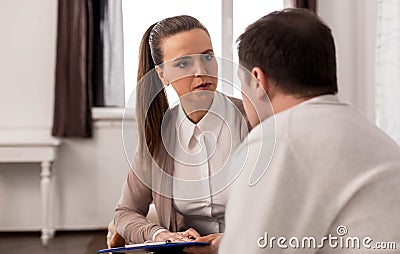 Serious confident therapist looking at her patient Stock Photo