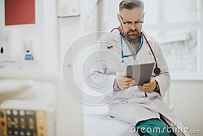 Serious doctor reading from a tablet Stock Photo