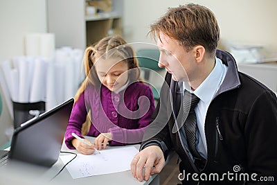 Serious father looks at his little daughter drawing picture Stock Photo