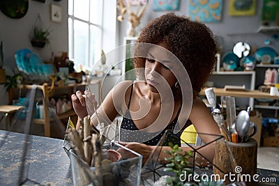 Focused brunette lady creating a florarium at professional studio Stock Photo