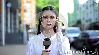 Serious female reporter with microphone in front of camera, breaking news Stock Photo