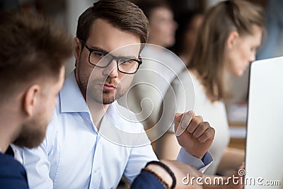 Serious focused male employee listening to colleague Stock Photo