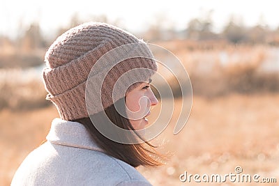 A serious girl in a knitted hat stands against a background and a coat against the backdrop of an autumn pale river landscape Stock Photo