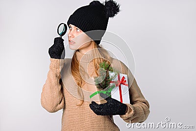 Serious girl with magnifying glass looking for Christmas discounts. White background Stock Photo