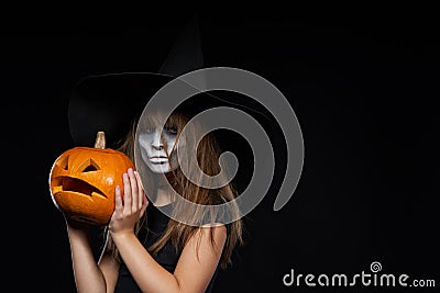 Serious Halloween witch holding Jack-O-Lantern pumpkin looking at camera Stock Photo