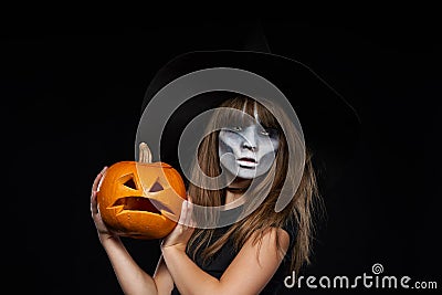 Serious Halloween witch holding Jack-O-Lantern pumpkin looking at camera Stock Photo