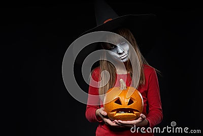 Serious Halloween witch holding Jack O`Lantern pumpkin looking at camera Stock Photo