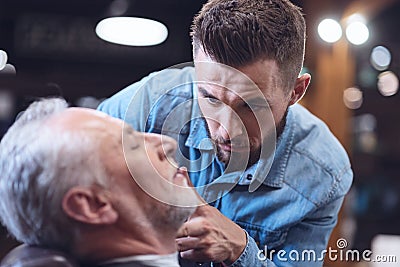 Serious handsome hairdresser looking at his client Stock Photo