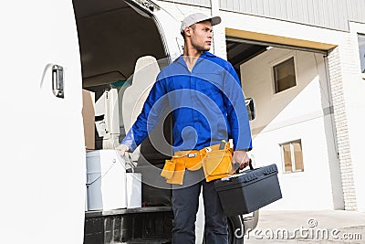 Serious handsome handyman holding toolbox Stock Photo