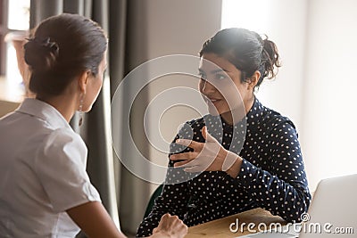 Serious indian mentor worker talk to female colleague teach intern Stock Photo