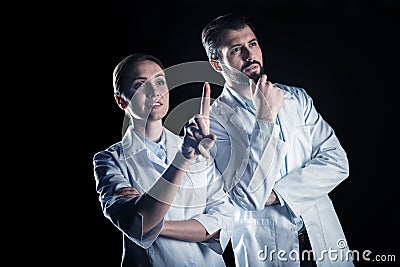 Serious intelligent scientists standing against black background Stock Photo