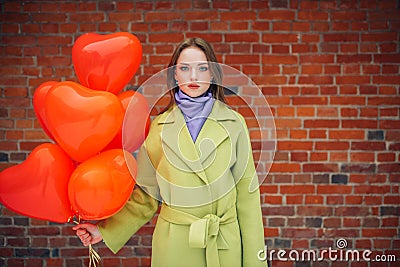 Serious lady in coat with red air balloons Stock Photo