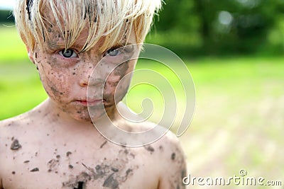 Serious Little Boy Covered in Dirt and Mud Outside Stock Photo