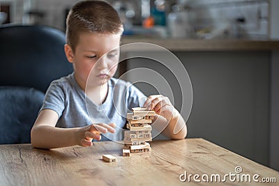 Serious little boy playing board game with wooden turret Stock Photo