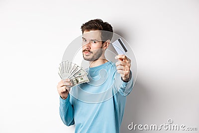 Serious-looking guy stretch out hand with plastic credit card, prefer contactless payment instead of cash, standing on Stock Photo