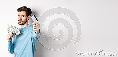 Serious-looking guy stretch out hand with plastic credit card, prefer contactless payment instead of cash, standing on Stock Photo