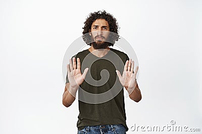 Serious looking man stretching out hand, showing stop rejection gesture, saying no, decline something, standing over Stock Photo