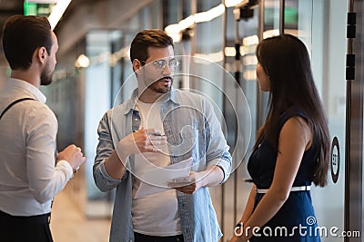 Serious male business leader instructing diverse employees standing in office Stock Photo