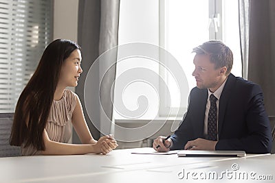 Serious hr employer listening to asian applicant at job interview Stock Photo