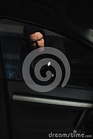 serious male robber in black hoodie with flashlight looking Stock Photo