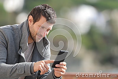 Serious man checking mobile phone app in winter Stock Photo