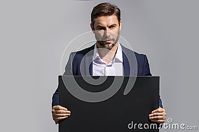 Serious man holds the sign, blank card. Placard ready for your product. Sign to your text. Handsome man showing blank Stock Photo