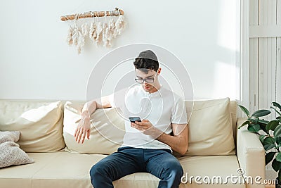 A serious man sits on a sofa and watches world news or solves business problems in a business at home. Stock Photo