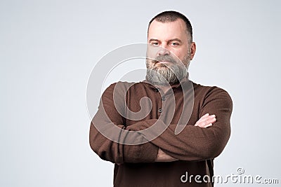 Serious mature european man standing with arms folded Stock Photo