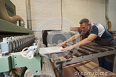 Competent aged carpenter gluing borders of veneer Stock Photo