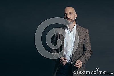 Serious middle aged man with a deadpan face expression dressed in casual posing on a dark gray background Stock Photo