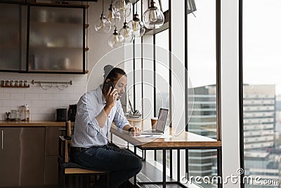 Serious african guy sit by pc screen speak by cell Stock Photo