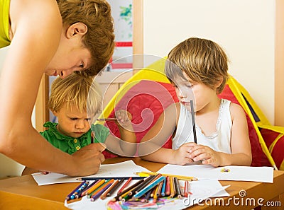 Serious mother and children drawing with pencils Stock Photo