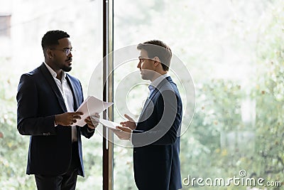 Diverse male business partners discuss paperwork in office Stock Photo