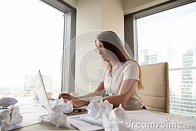 Serious overwhelmed businesswoman working on laptop surrounded b Stock Photo