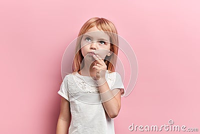 Serious pensive girl with a finger on her chin looking up Stock Photo