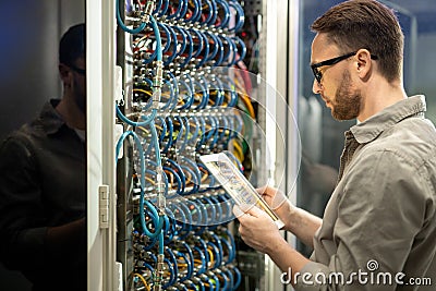 Data center technician checking connections on tablet Stock Photo