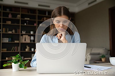 Serious pensive young employee working at laptop from home Stock Photo