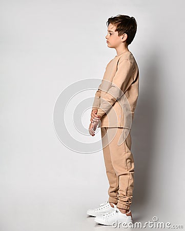 Serious preteen boy child standing sideway looking forward over studio wall Stock Photo