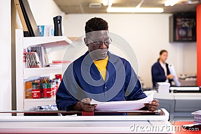 Serious print shop worker cuts paper on professional cutter Stock Photo