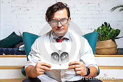 Serious professional psychologist showing paper with Rorschach inkblot Stock Photo