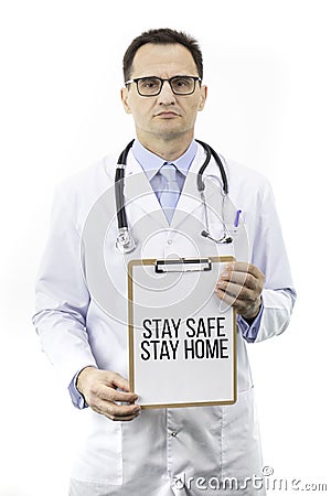 Serious senior age doctor shows clipboard with text Stay home Stay safe covid-19 Stock Photo