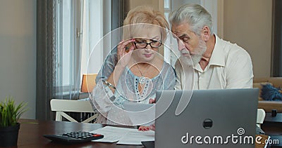 Serious senior old couple talking disputing holding paper bills checking finances expenses, older middle aged family Stock Photo