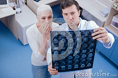 Serious shocked woman looking at her brain X ray images Stock Photo