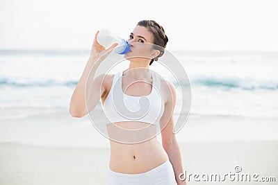 Serious slim brown haired model in white sportswear drinking water Stock Photo