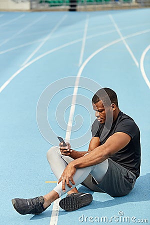 Serious sporty guy sending message, sms to his friends Stock Photo