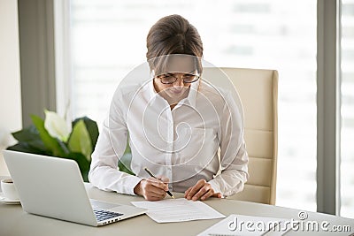 Serious successful businesswoman puts signature on business cont Stock Photo