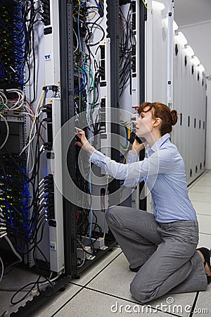 Serious technician talking on phone while analysing server Stock Photo